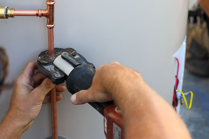 Plumber fitting copper pipes to a hot water system in Nambour